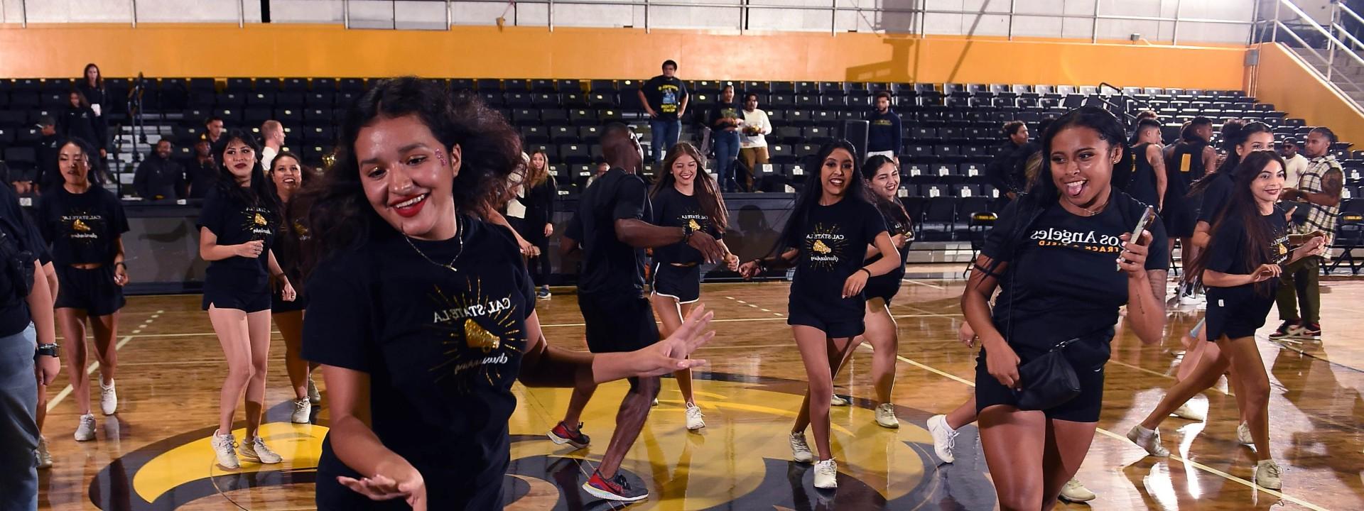 Dance team in identical t-shirts and shorts smiling mid-dance step.